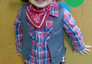 Uśmiechnięty chłopiec pozuje do zdjęcia jako Kowboy.