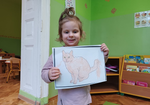 Dziewczynka pokazuje rysunek kota.
