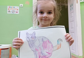 Dziewczynka pokazuje rysunek kota.