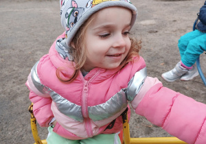 Uśmiechnięta dziewczynka kręci się na karuzeli.